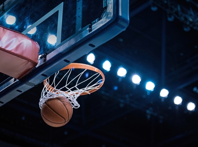 Basketball scoring through the hoop inside a professional indoor arena. | Huber Fox