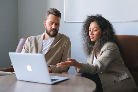 a woman presenting work in a laptop to a man