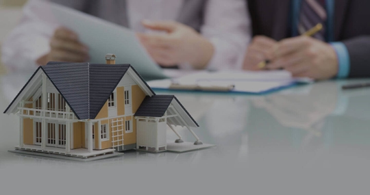 model of house and clients with documents in the background