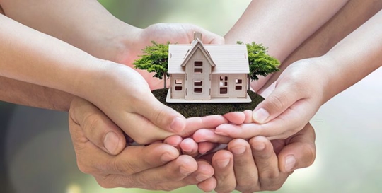 many hands holding model of house